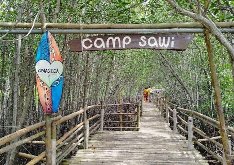 A wooden bridge leading to a camp named 'camp sawi' with a colorful sign on the left. 3