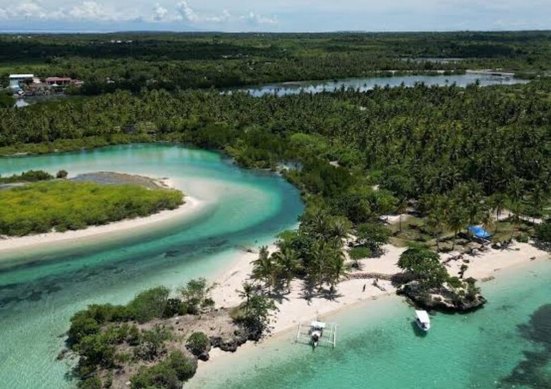 A coastal landscape with a sandy beach, turquoise waters, and dense greenery. 2