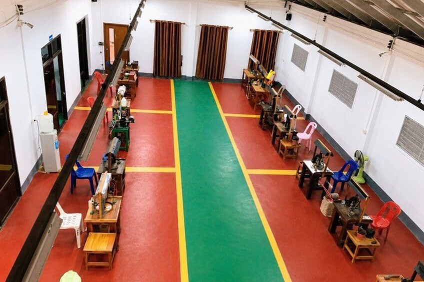 A room with a red and green floor, rows of tables, chairs, and various equipment. 2