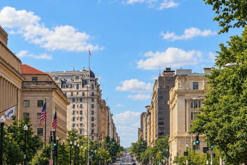 A city street with historic buildings, American flags, and a clear blue sky. 4