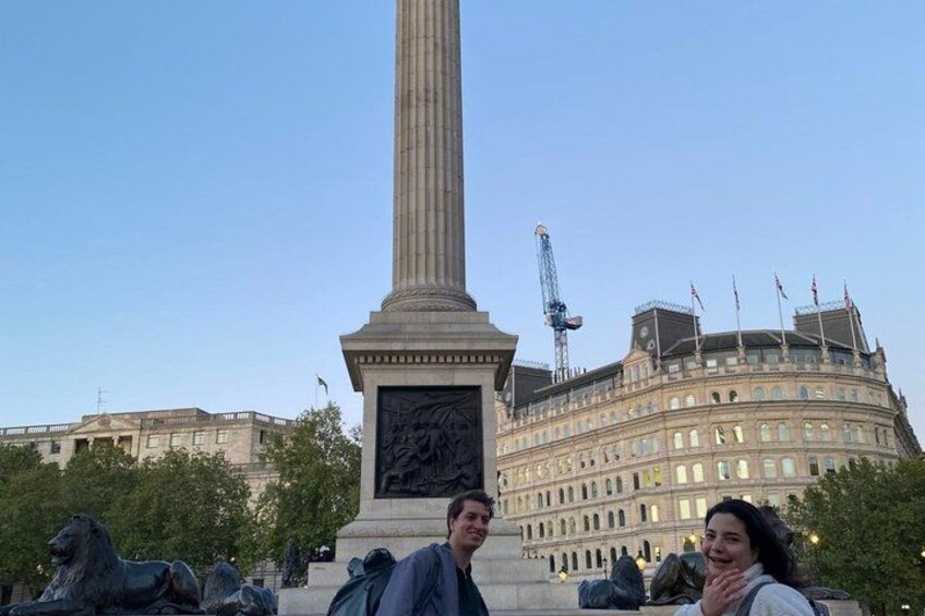 A tall monument with a statue base, surrounded by statues, in front of a large building with multiple flags. 2