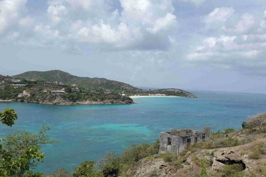 A coastal landscape with clear turquoise waters, a small island with buildings, and a rocky foreground. 2
