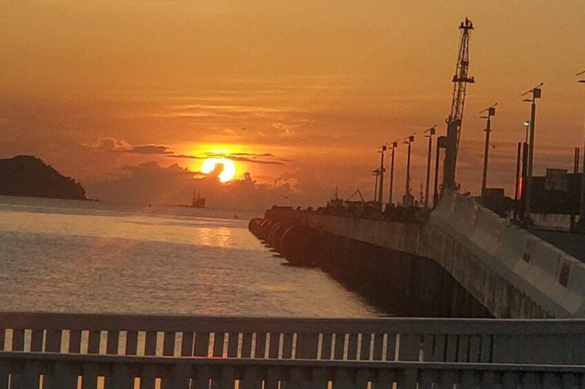 A sunset over a body of water with a pier and industrial structures. 3
