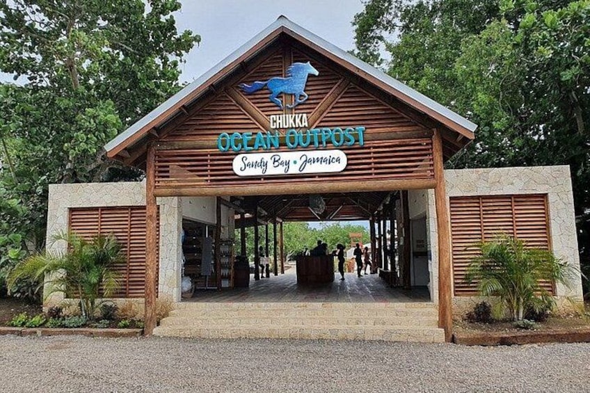 A wooden building with a sign reading 'Chuka Ocean Outpost' and 'Sandy Bay Jamaica'. 3