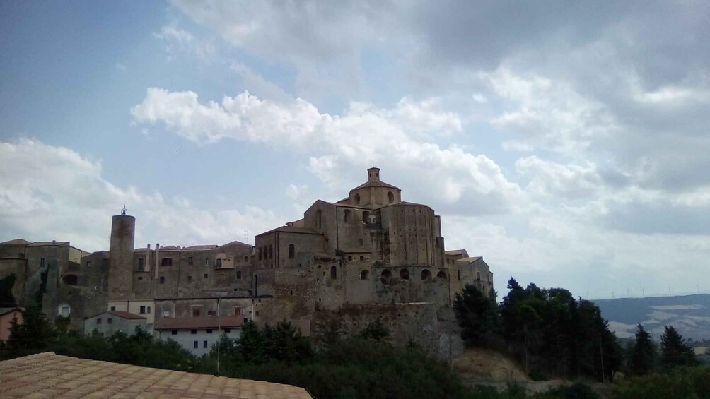 Un bâtiment historique à plusieurs étages, surmonté d’un dôme imposant, entouré d’arbres et se dressant sous un ciel partiellement nuageux. 4