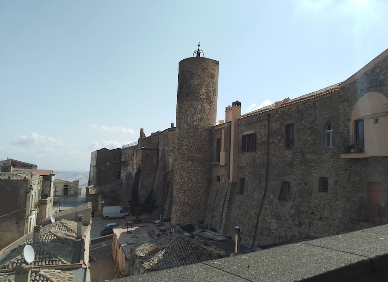 Un bâtiment historique en pierre, doté d’une tour cylindrique, d’un balcon et surplombant un ciel dégagé. 1