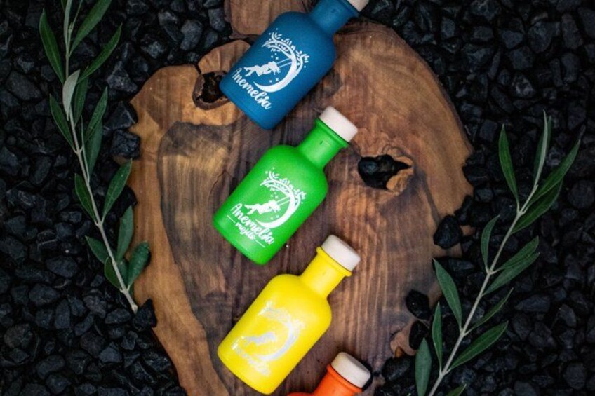 Three bottles of beverages on a wooden surface surrounded by black pebbles and green leaves. 3