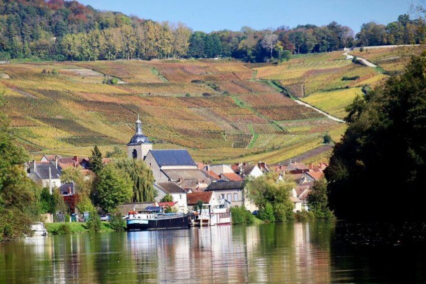 A river with a boat, a church, and houses on a hillside. 3