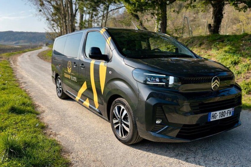 A black Citroën C3 van with yellow and black stripes parked on a rural road. 4