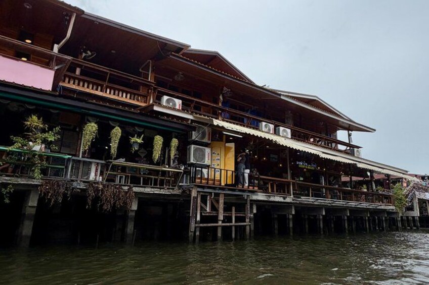 A traditional wooden building with a balcony, overwater structure, and potted plants. 3