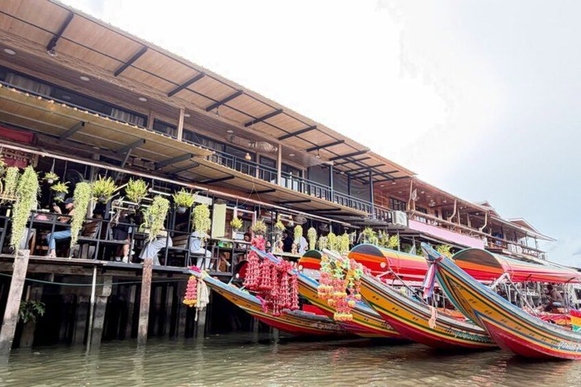 A riverside building with colorful boats docked in front. 4