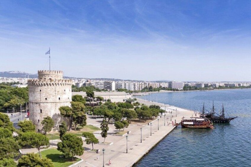 A coastal cityscape with a historic tower, a promenade, and a ship docked at the harbor. 5