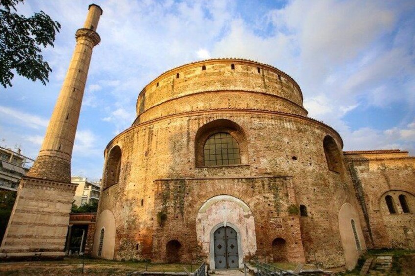 A historic building with a round central structure, arched windows, and a tall chimney. 2