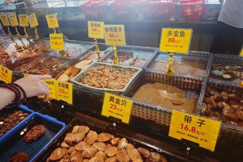 A variety of seafood and dried goods displayed in a market stall with price tags. 5