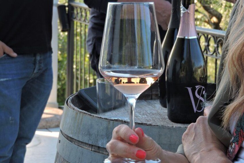A person holding a wine glass, a wine bottle, and a barrel. 2