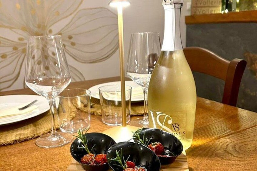 A dining table with a bottle of white wine, glasses, and black bowls with food. 5