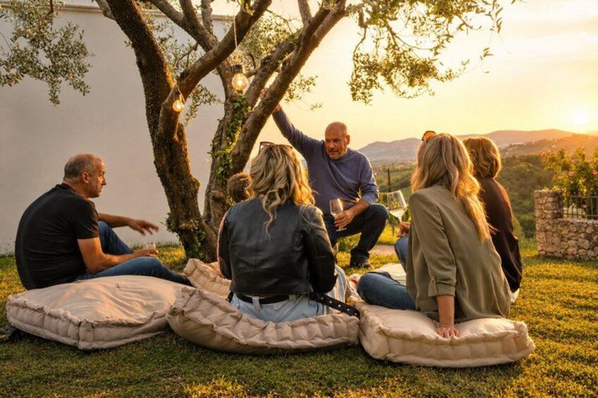 A group of people sitting on cushions outdoors during sunset. 3