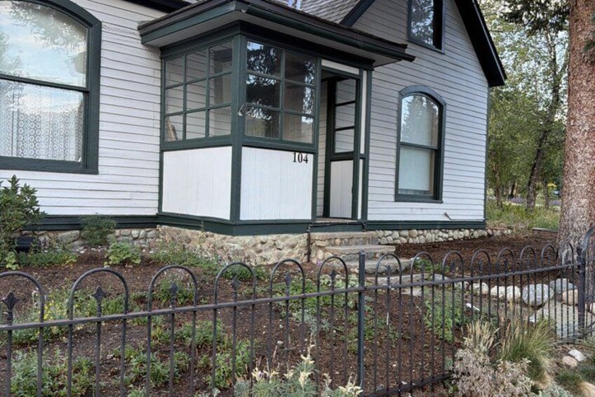 A house with a bay window, a stone foundation, and a metal fence. 2
