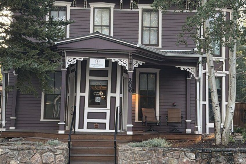 A two-story house with a porch, a mailbox, and a stone wall in front. 3