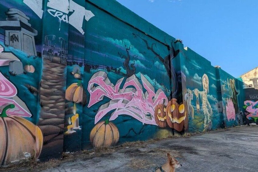 A mural with pumpkins and graffiti on a wall. 4
