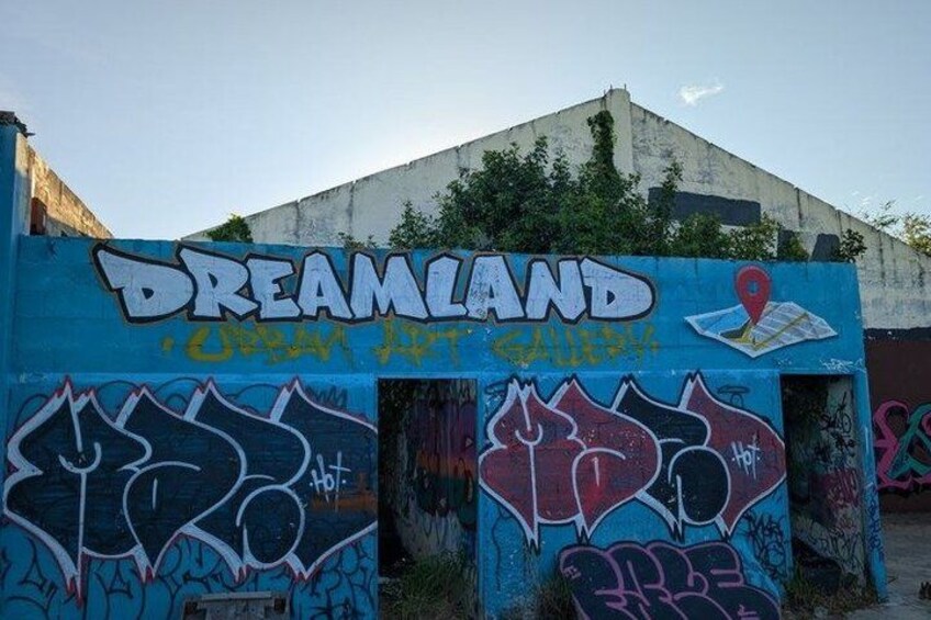 A wall with graffiti and the words 'DREAMLAND' and 'Urban Art Gallery'. 1