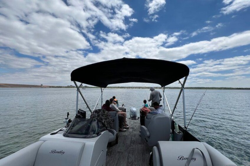 A boat with a canopy, people sitting, and calm water. 3
