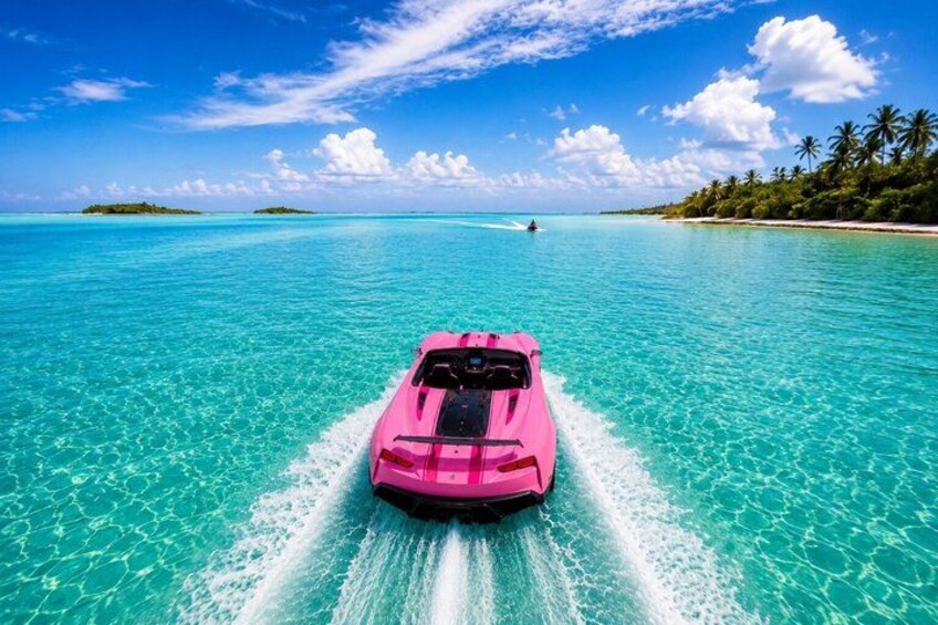 Un bote rosa avanza rápidamente sobre aguas turquesas, bajo un cielo despejado y con islas distantes en el horizonte. 1