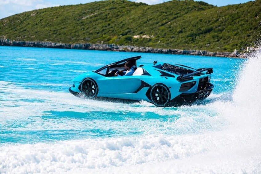 Un coche deportivo azul circulando sobre una superficie acuática turquesa con olas a su alrededor. 3