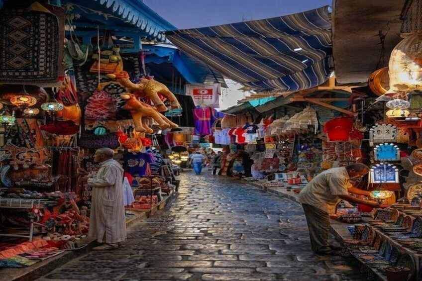 A bustling market with various stalls selling colorful textiles and goods. 3