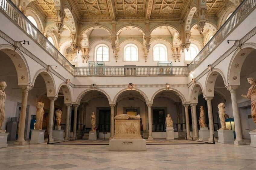 A grand hall with high ceilings, arched columns, and statues. 2