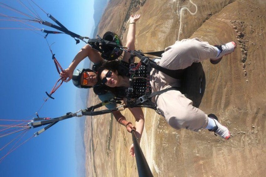 Two people paragliding with a rocky landscape in the background. 5