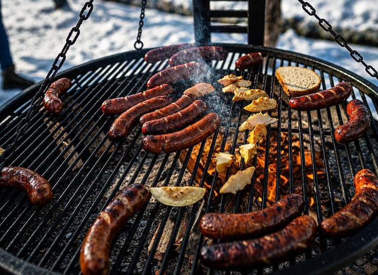 Un barbecue avec des saucisses et du poulet en train de cuire à l’extérieur. 4