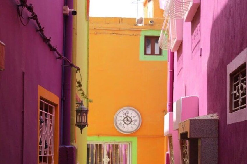 A narrow alley with colorful buildings, a clock, and a lantern. 3