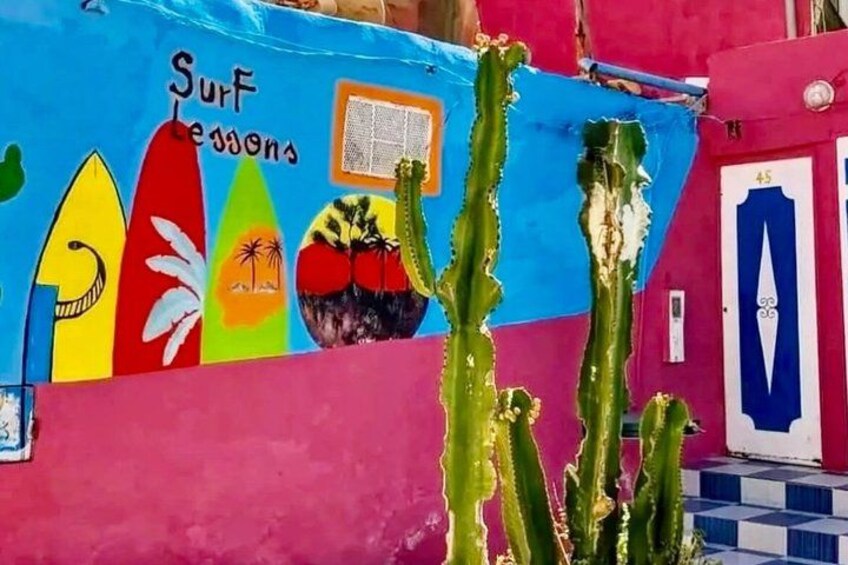 A colorful mural with surfboards and a cactus. 2
