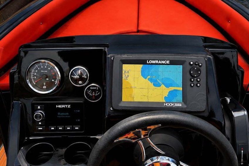 A dashboard with a Lowrance GPS device, a HERTZ radio, and a steering wheel. 3