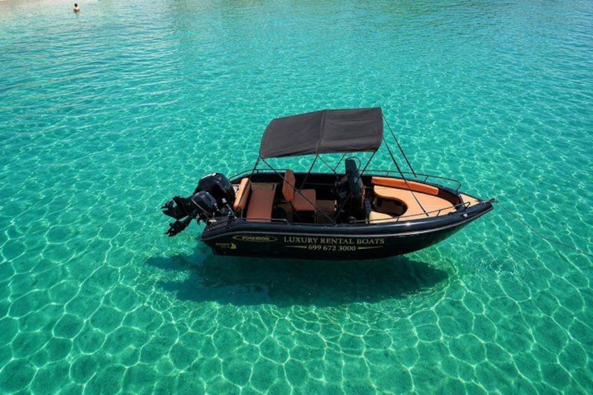 A small motorboat with a canopy, floating on clear turquoise water. 4