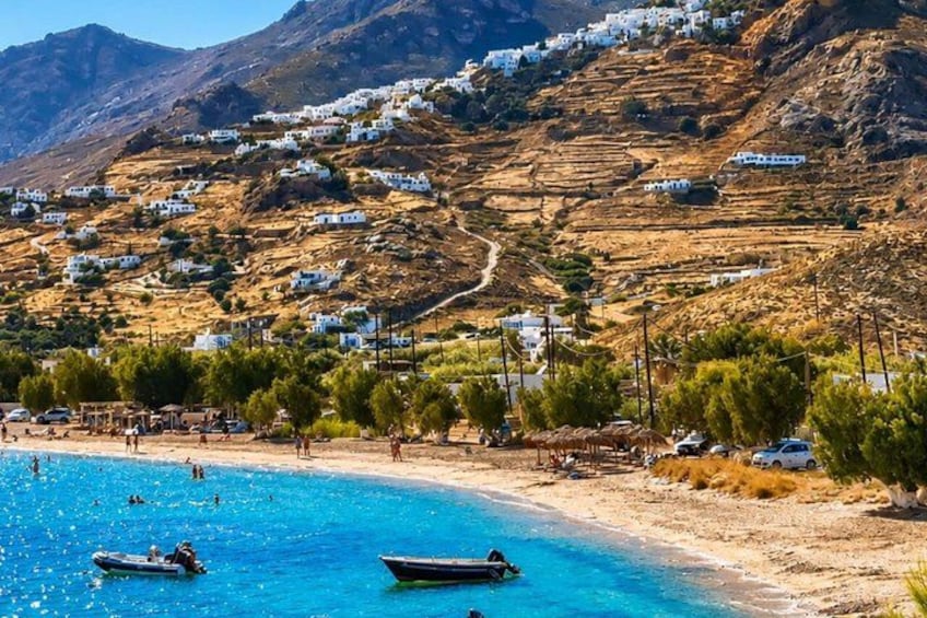 A coastal village with white houses on a hillside, a sandy beach, and clear blue water. 2