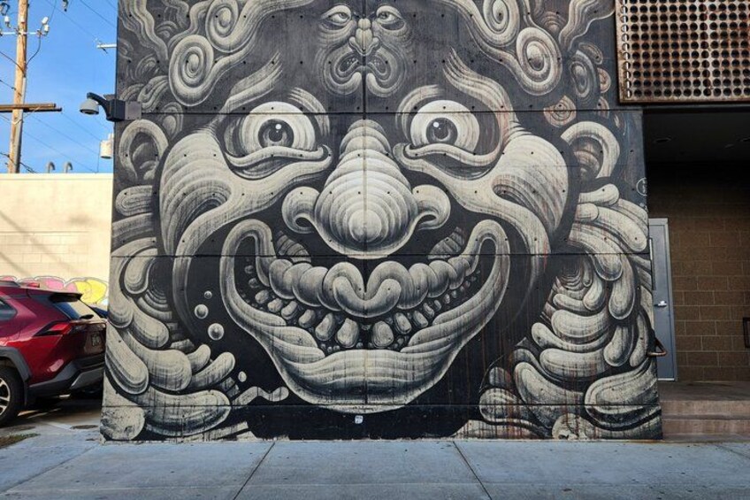 A large mural of a smiling face with intricate patterns on a wall. 2