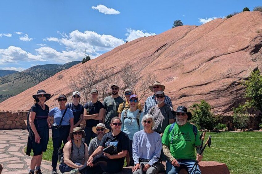 A group of people posing in a natural landscape with red rock formations and a clear sky. 1