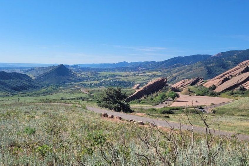A mountainous landscape with a clear sky, a winding road, and scattered trees. 3
