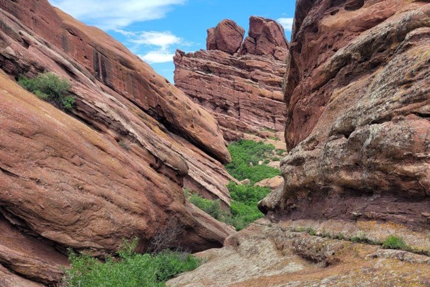 A canyon with red rock formations and green vegetation. 2