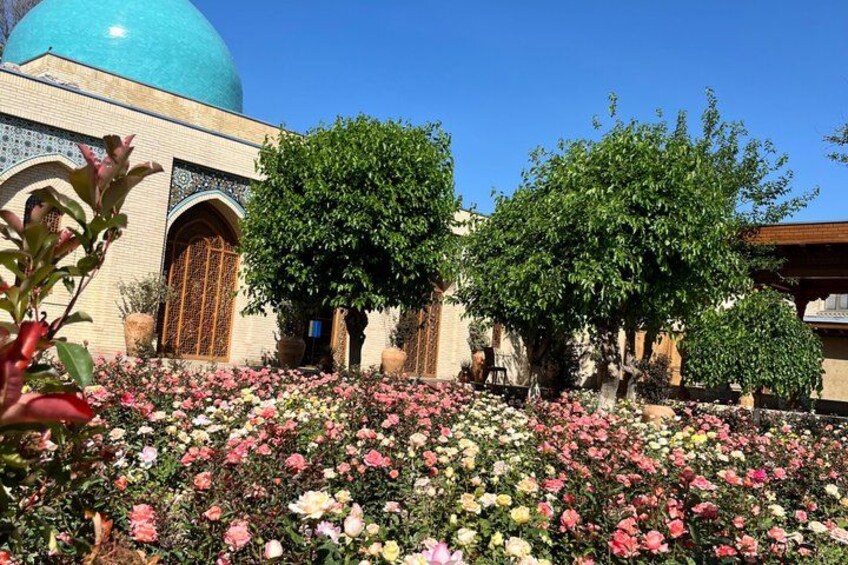 A mosque with a blue dome, surrounded by a garden with various flowers. 1