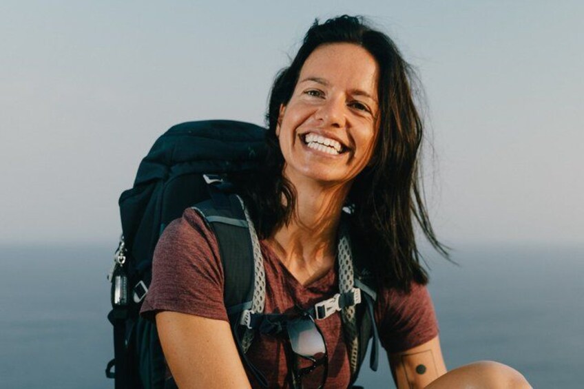 A person with a backpack, wearing a short-sleeved top, sitting outdoors. 3