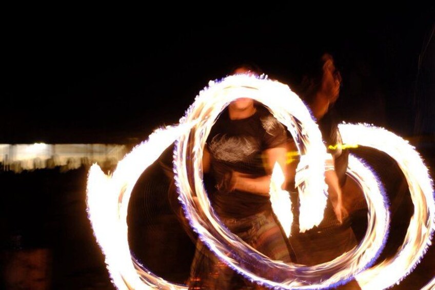 A person performing fire spinning with a circular fire pattern. 4