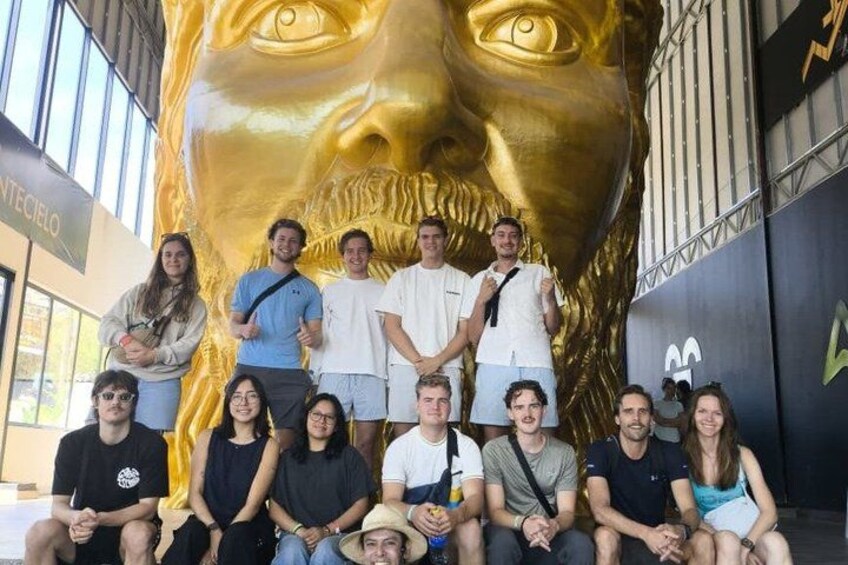 A group of people posing in front of a large golden statue. 2