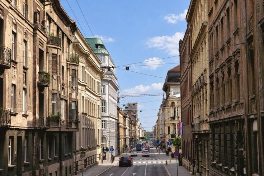 A street lined with historic buildings, a pedestrian crossing, and a clear sky. 4