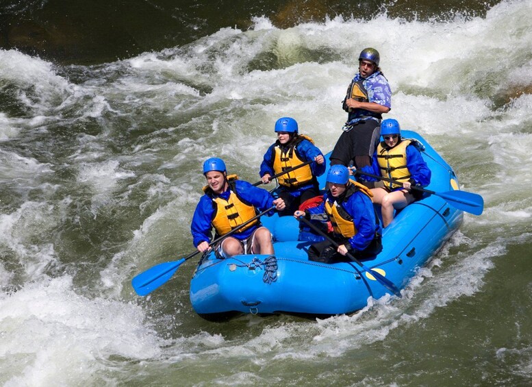 Un groupe de personnes fait du rafting sur un radeau gonflable bleu dans une rivière aux eaux tumultueuses et aux rapides. 2