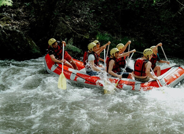 Un groupe de personnes à bord d’un radeau rouge naviguant sur une rivière. 1