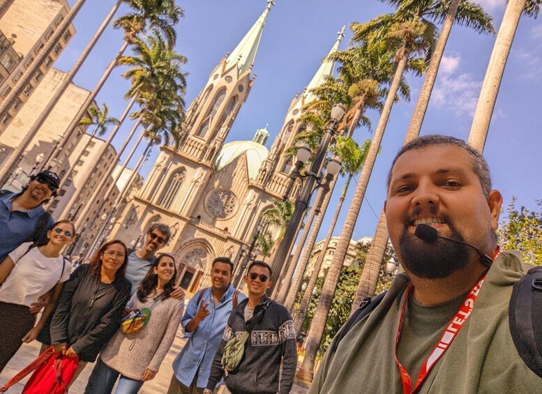 A group of people standing in front of a historic building with a spire and palm trees. 1