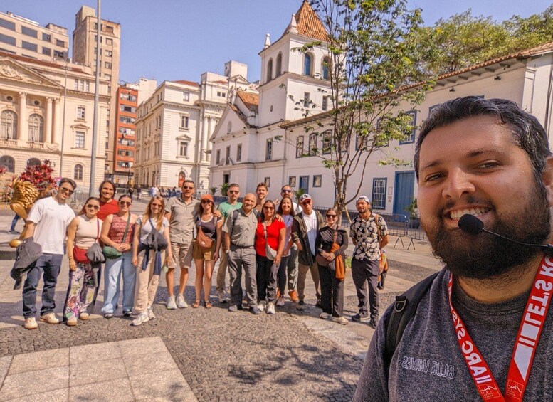 A group of people standing in a cobblestone square with historic buildings and a church in the background. 4